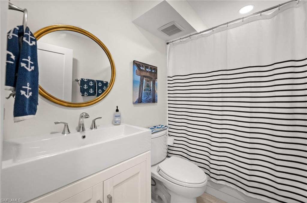 1021 3rd Street South, Unit 112 Naples, FL 34102 - Photo 21 of 27 a bathroom with a sink a mirror a toilet and a shower