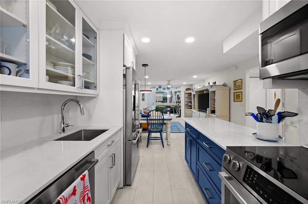 1021 3rd Street South, Unit 112 Naples, FL 34102 - Photo 9 of 27 a kitchen with stainless steel appliances a sink stove and cabinets