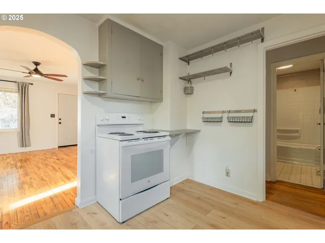 a view of kitchen and empty room with wooden floor