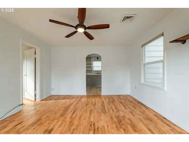 a view of a big room with wooden floor and windows