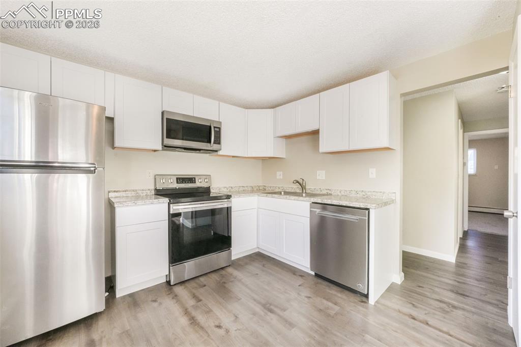 6610 Dublin Loop West, Unit 2 Colorado Springs, CO 80918 - Photo 12 of 50 a kitchen with a refrigerator stove and white cabinets