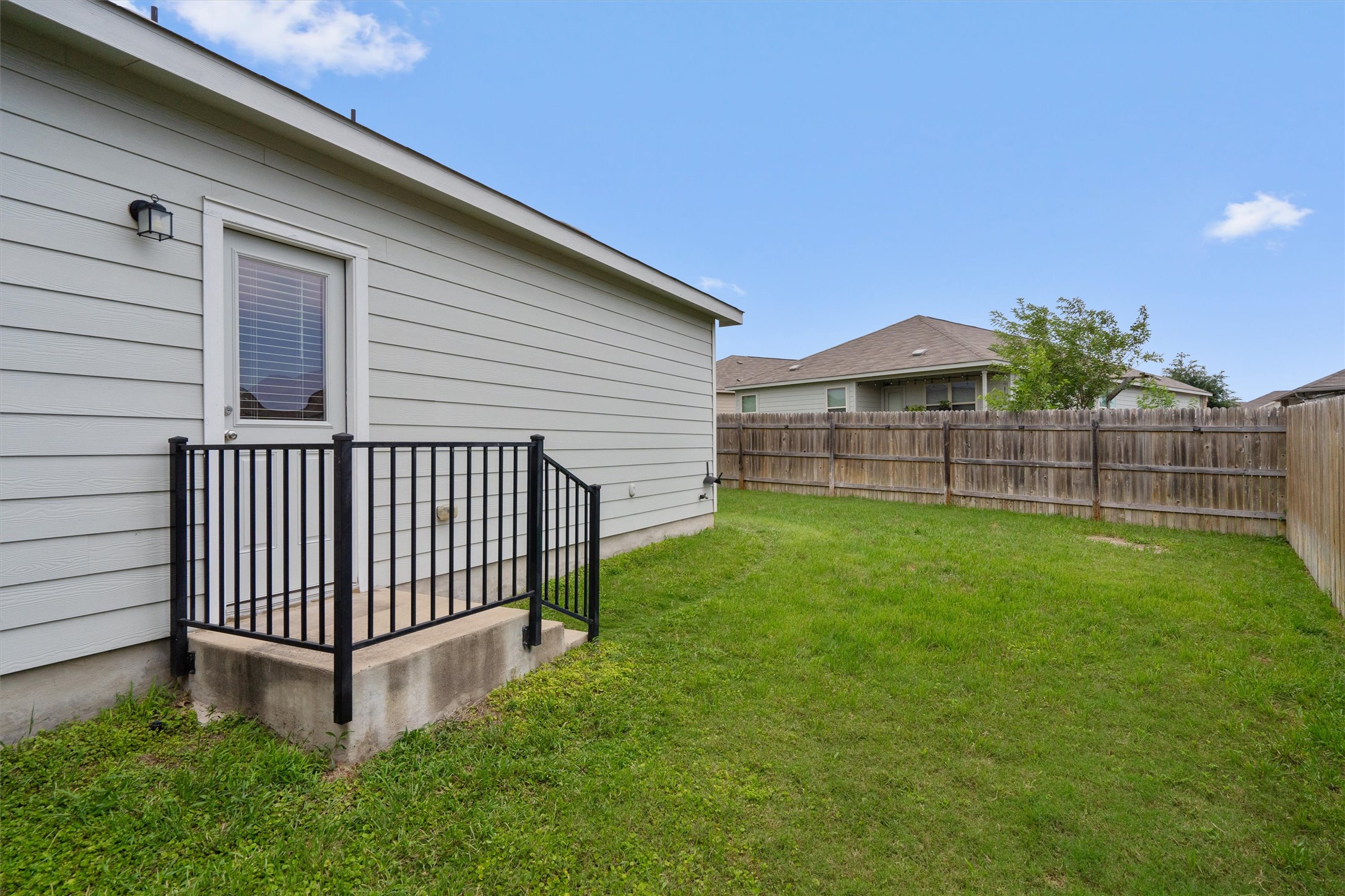 791 Circle Way Jarrell, TX 76537 - Photo 29 of 36 Expansive backyard featuring a manicured lawn, a full wood privacy fence, and a concrete patio with black metal railing