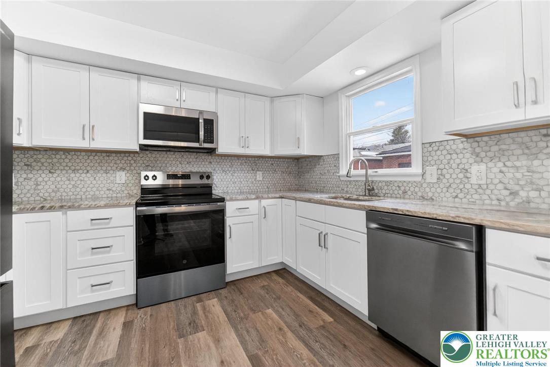 708 Cherokee Street Bethlehem, PA 18015 - Photo 9 of 25 a kitchen with stainless steel appliances granite countertop white cabinets a sink a stove a microwave and cabinetry
