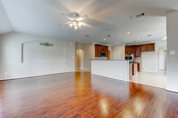 a view of a big room with wooden floor and a kitchen
