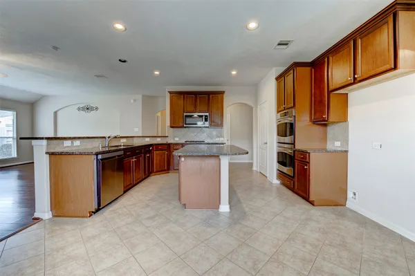 a kitchen with stainless steel appliances granite countertop a stove top oven a sink and a refrigerator