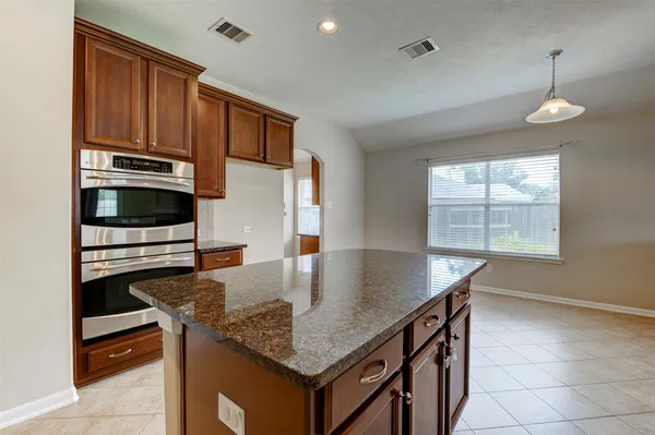 a kitchen with stainless steel appliances granite countertop a stove a kitchen island a stove and a window