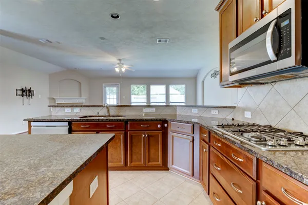 a kitchen with stainless steel appliances granite countertop a stove a sink and a microwave