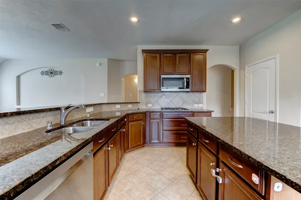 a kitchen with granite countertop a sink and a stove top oven with wooden cabinets