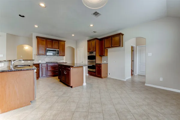 a large kitchen with a large counter top stainless steel appliances and cabinets