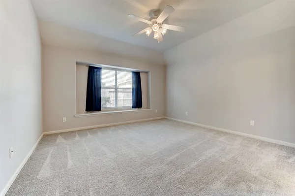 an empty room with windows and ceiling fan