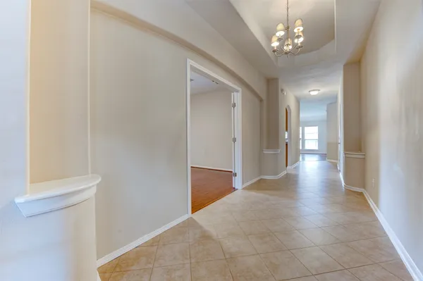 a view of a hallway with chandelier and glass door
