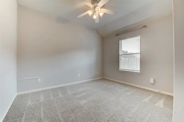 an empty room with a window and a fan