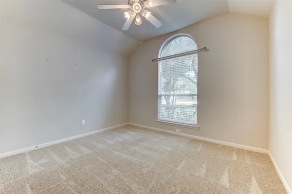 an empty room with a chandelier fan and a window