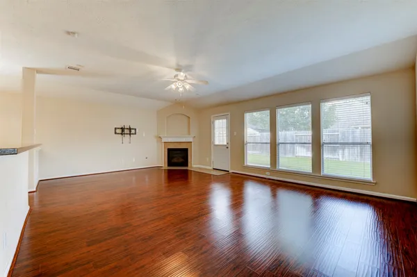 a view of an empty room with wooden floor and a window