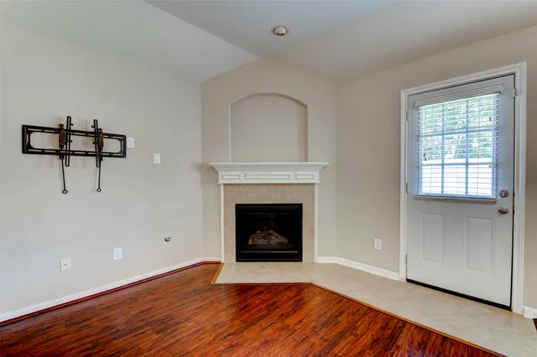 a view of an empty room with wooden floor fireplace and a window