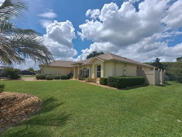 a view of a house with a big yard plants and large trees