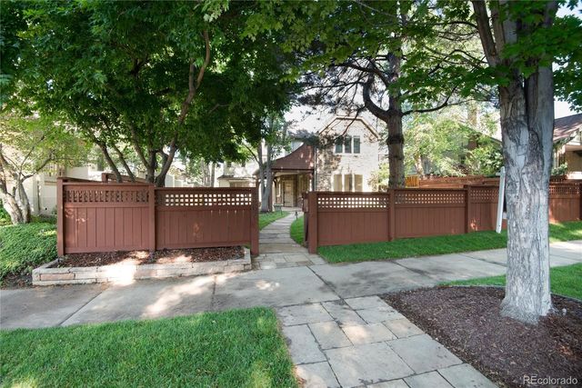 a view of backyard with large trees and wooden fence