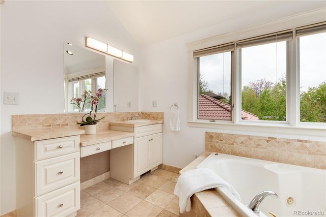 a bathroom with a granite countertop sink mirror bathtub and next to a window