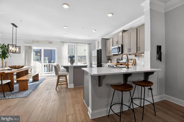 a kitchen with stainless steel appliances granite countertop a stove top oven a sink dishwasher a dining table and chairs with wooden floor