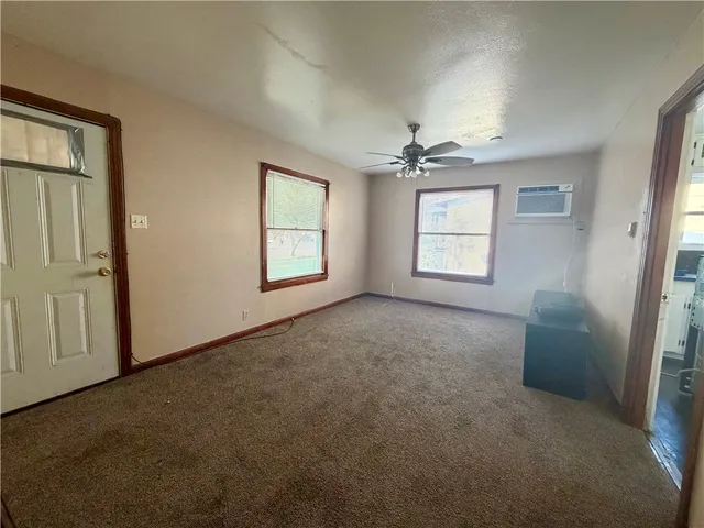 an empty room with windows and chandelier fan