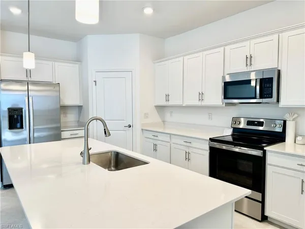 a kitchen with stainless steel appliances a sink a stove a microwave a sink a refrigerator and cabinets