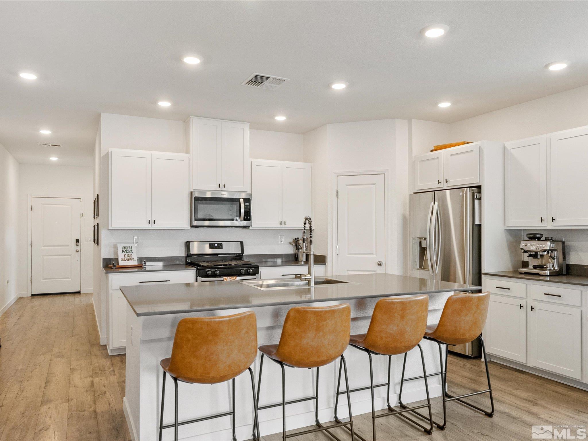 1173 Alder Drive Fallon, NV 89406 - Photo 9 of 40 a kitchen with stainless steel appliances granite countertop a stove a sink a microwave a refrigerator and white cabinets with wooden floor