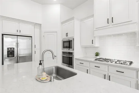 a kitchen with stainless steel appliances a sink a stove top oven a counter space and cabinets