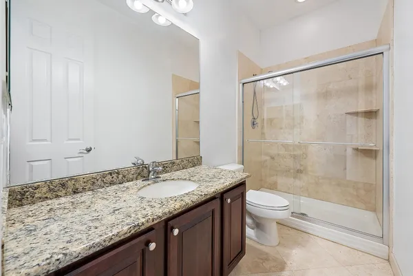a bathroom with a granite countertop sink a toilet and shower