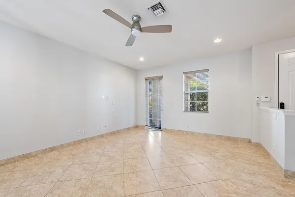 an empty room with windows and ceiling fan