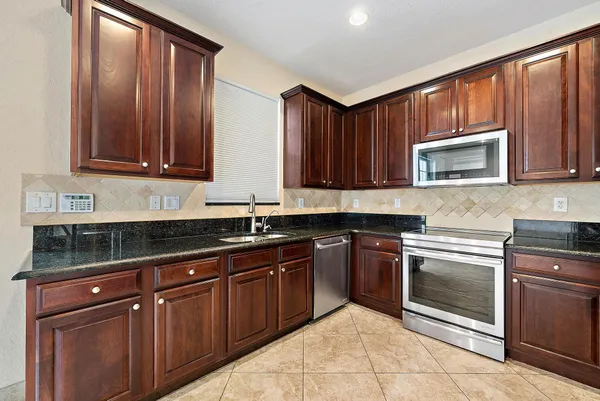 a kitchen with granite countertop wooden cabinets and stainless steel appliances