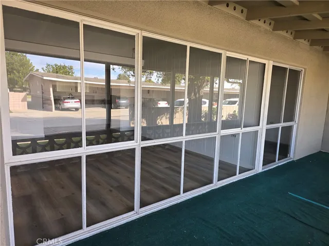 a view of an empty room with wooden floor and windows