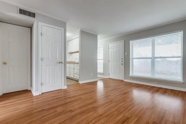 an empty room with wooden floor and windows