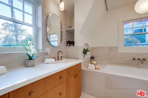 a bedroom with a bed a table and a dresser next to a window