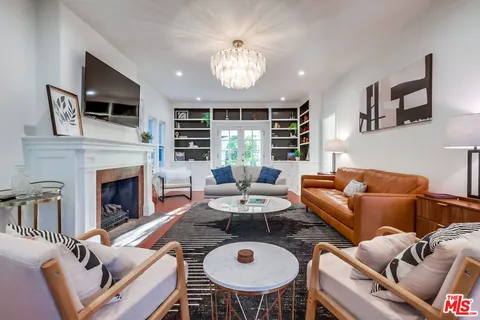 a living room with furniture a chandelier and a large mirror