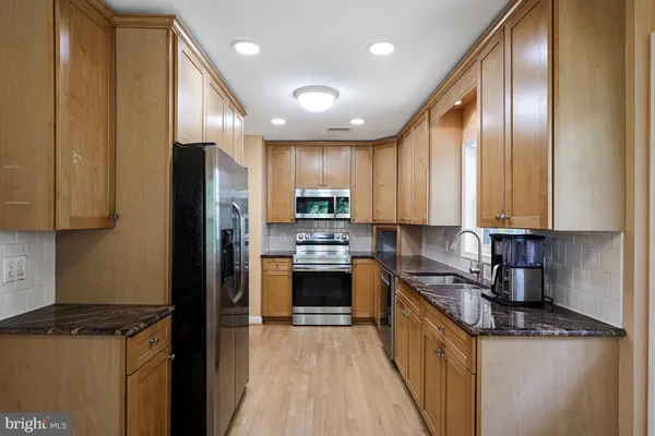 a kitchen with stainless steel appliances granite countertop a refrigerator a stove top oven a sink and dishwasher