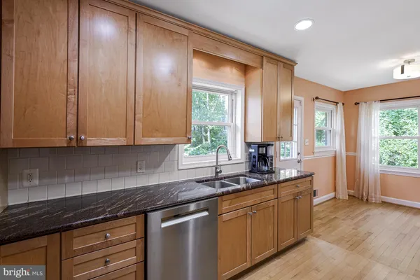 a kitchen with granite countertop cabinets stainless steel appliances a sink and a large window