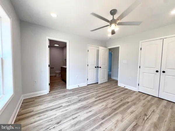 an empty room with wooden floor fan and windows