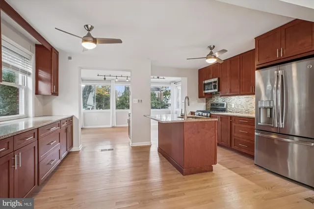 a kitchen with stainless steel appliances granite countertop a refrigerator a sink dishwasher a stove and a refrigerator with wooden floor