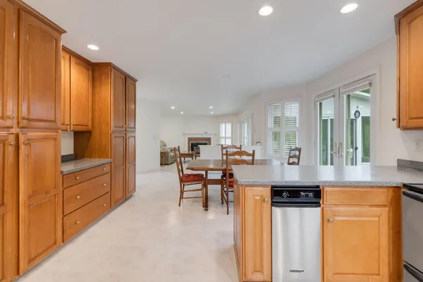 a room with stainless steel appliances kitchen island granite countertop a refrigerator a stove and a dining table with wooden floor