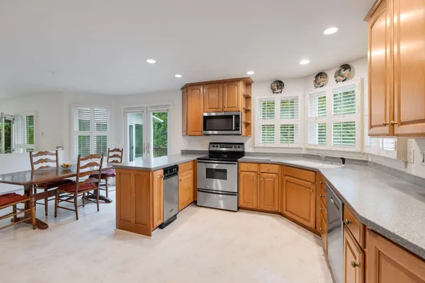 a kitchen with stainless steel appliances granite countertop a stove top oven a sink a dining table and chairs