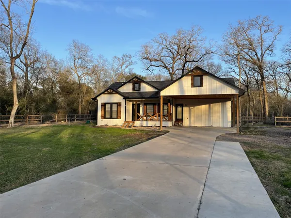 a front view of a house with a garden and trees