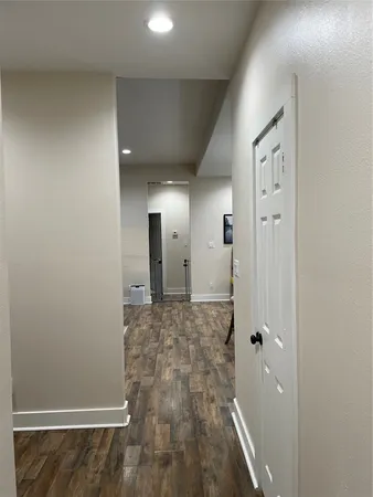 a view of a hallway with wooden floor and a bathroom
