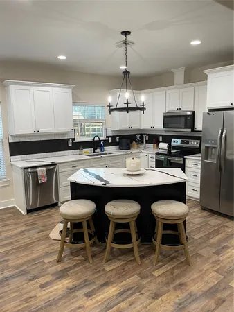 a kitchen with stainless steel appliances a dining table chairs and wooden floor