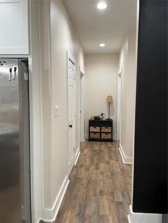 a view of a hallway with wooden floor and a bathroom