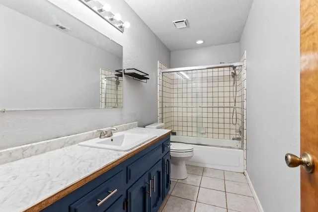 a bathroom with a granite countertop sink a toilet and shower