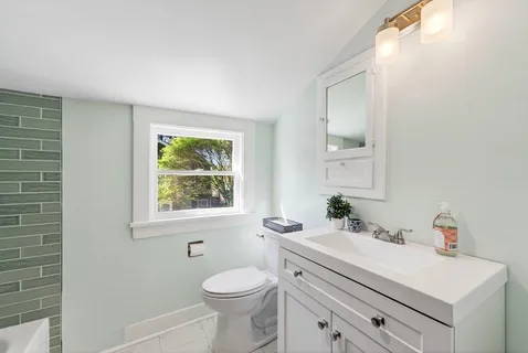 a bathroom with a sink a toilet and a window