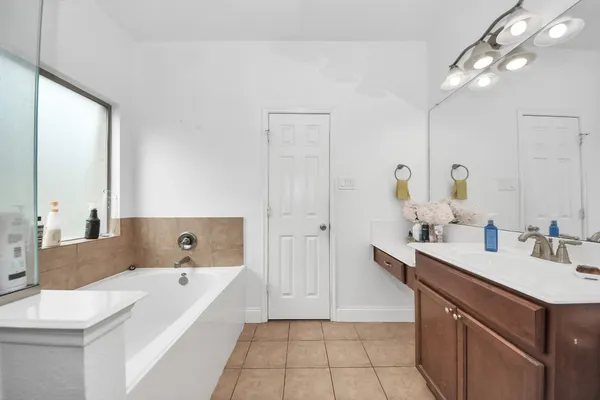 a spacious bathroom with a tub sink and mirror