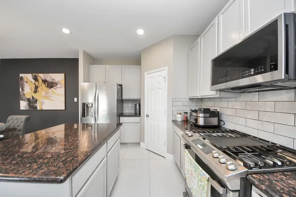 a kitchen with stainless steel appliances granite countertop a stove a sink and a microwave