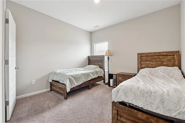 a bedroom with two beds and a lamp on the dresser