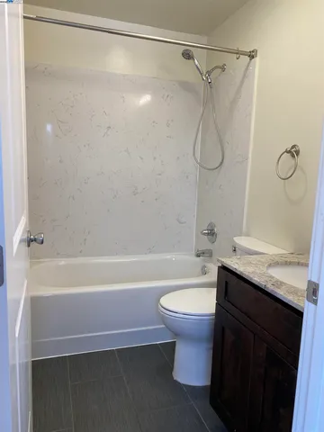 a bathroom with a granite countertop shower sink vanity mirror and toilet
